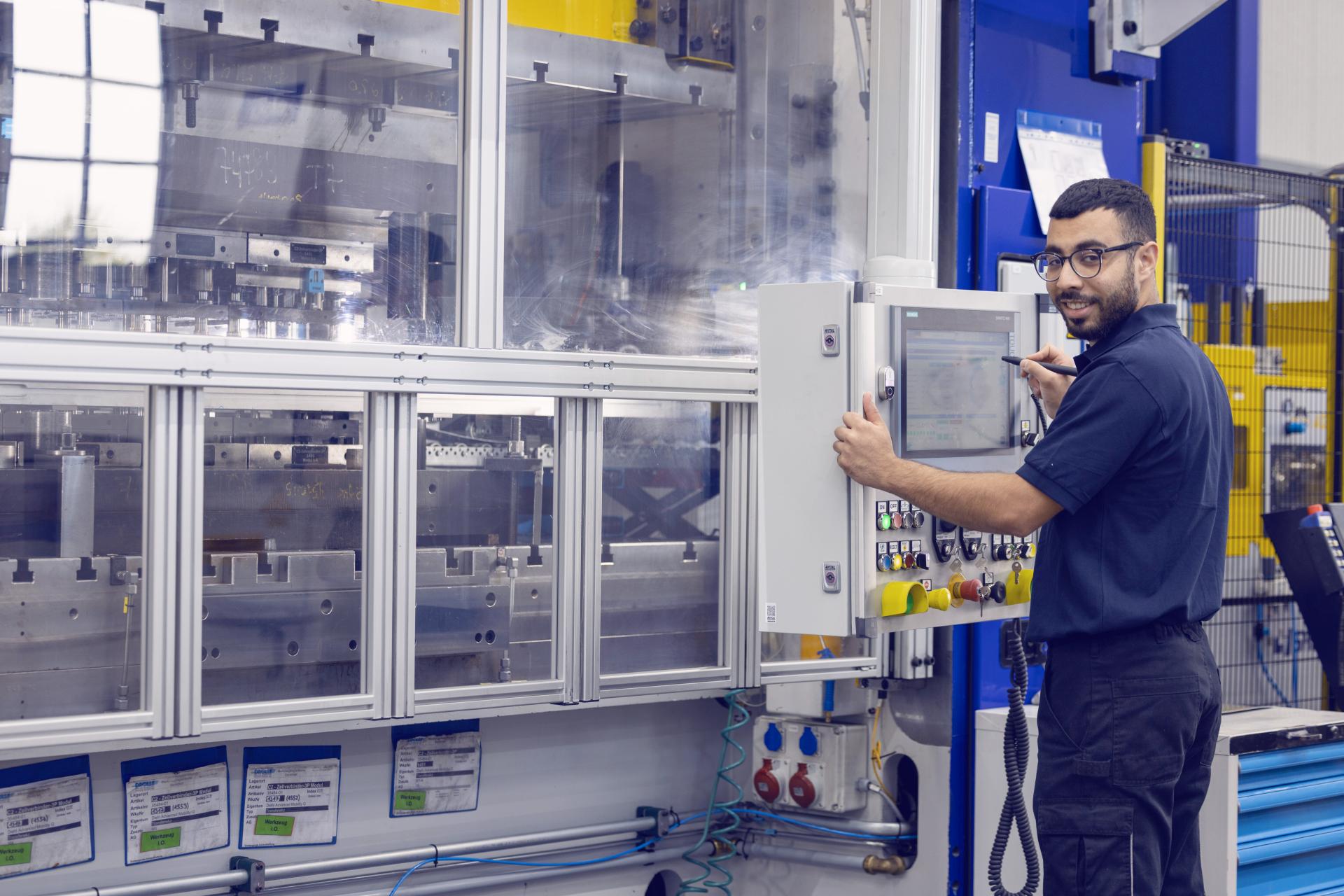 Junge Mitarbeiter schauen durch die Stanzpresse